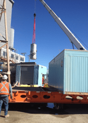 A crane lifting a blue container on top of a truck.
