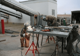 A man welding metal on top of a table.