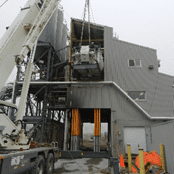 A crane is lifting a building onto the ground.