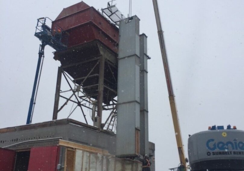 A crane is lifting the roof of a building.