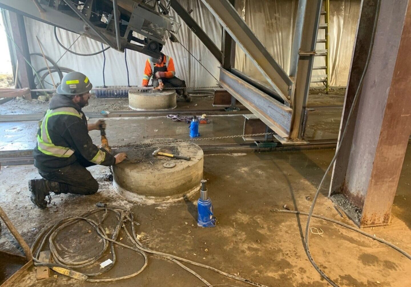 A man in yellow jacket working on concrete.