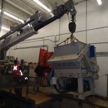 A crane is lifting a machine in the warehouse.